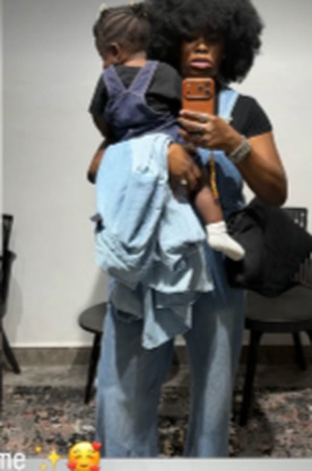 Treasure carrying her baby on her hip, taking a mirror selfie